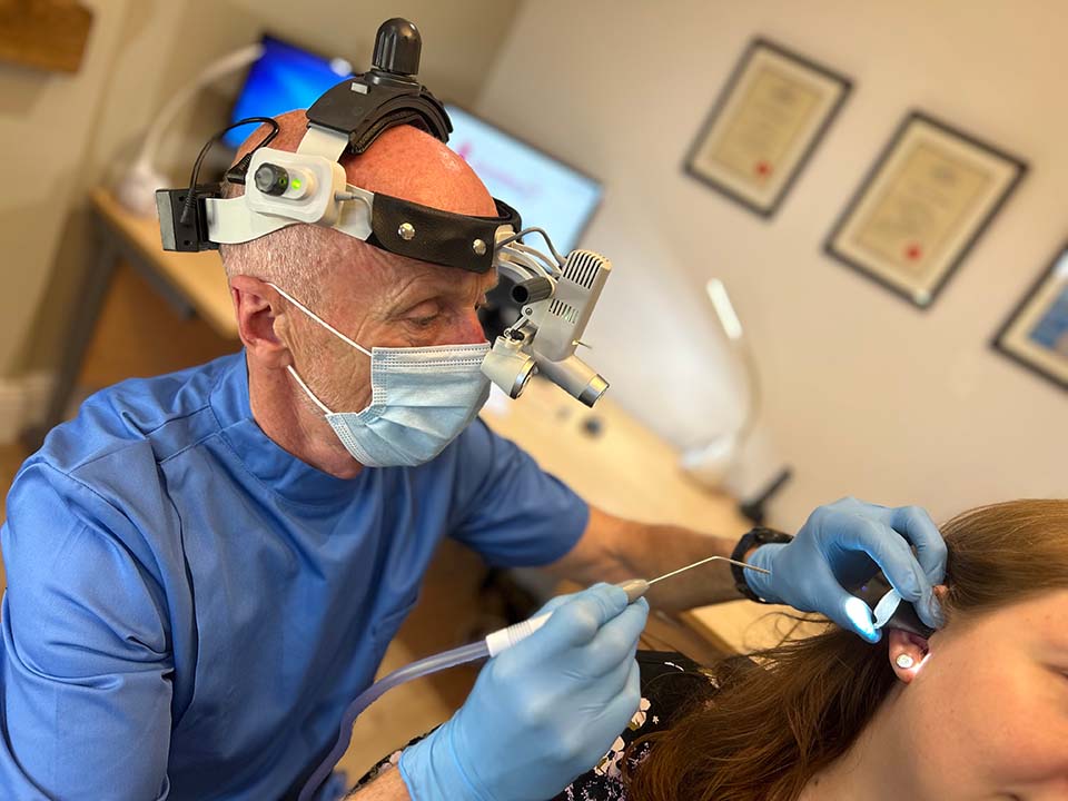 ear wax removal technician at work on female patient